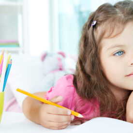 Portrait of lovely girl drawing with colorful pencils