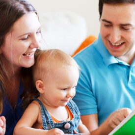 Young happy family with two kids drawing and reading together