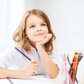 education and school concept - little student girl drawing with pencils at school